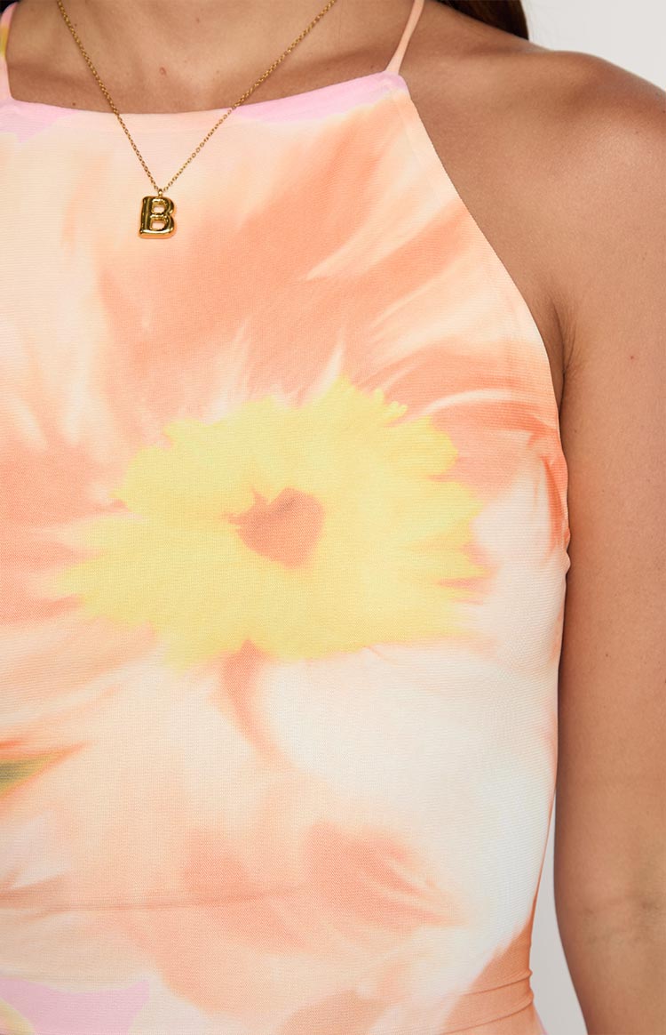 Close-up of the pink and orange floral print fabric with a large yellow flower motif and thin halter strap of the maxi dress