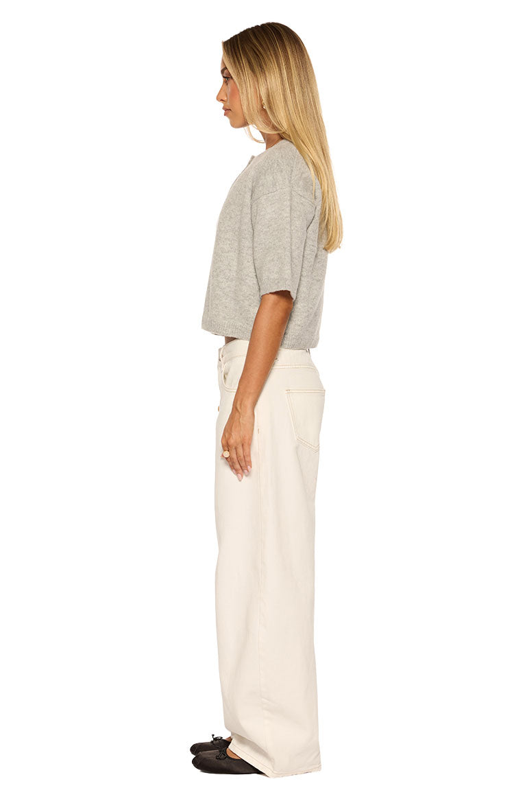 Side view of a light grey short sleeve cropped cardigan showing its relaxed fit and knit texture