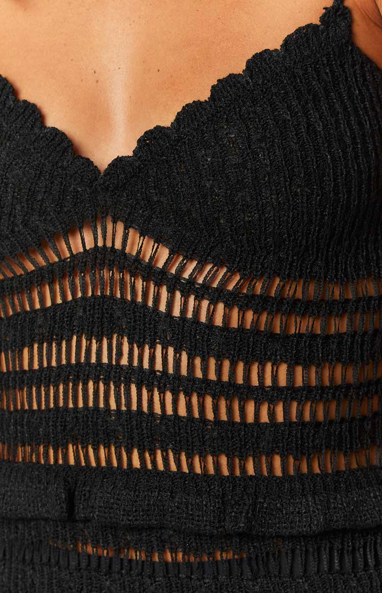 Close-up of the scalloped V-neckline and horizontal open-knit cutouts on a black knit mini dress