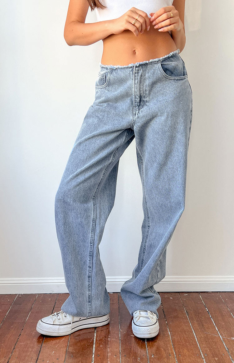 Full length view of mid wash blue denim jeans with a raw frayed waistband and wide legs