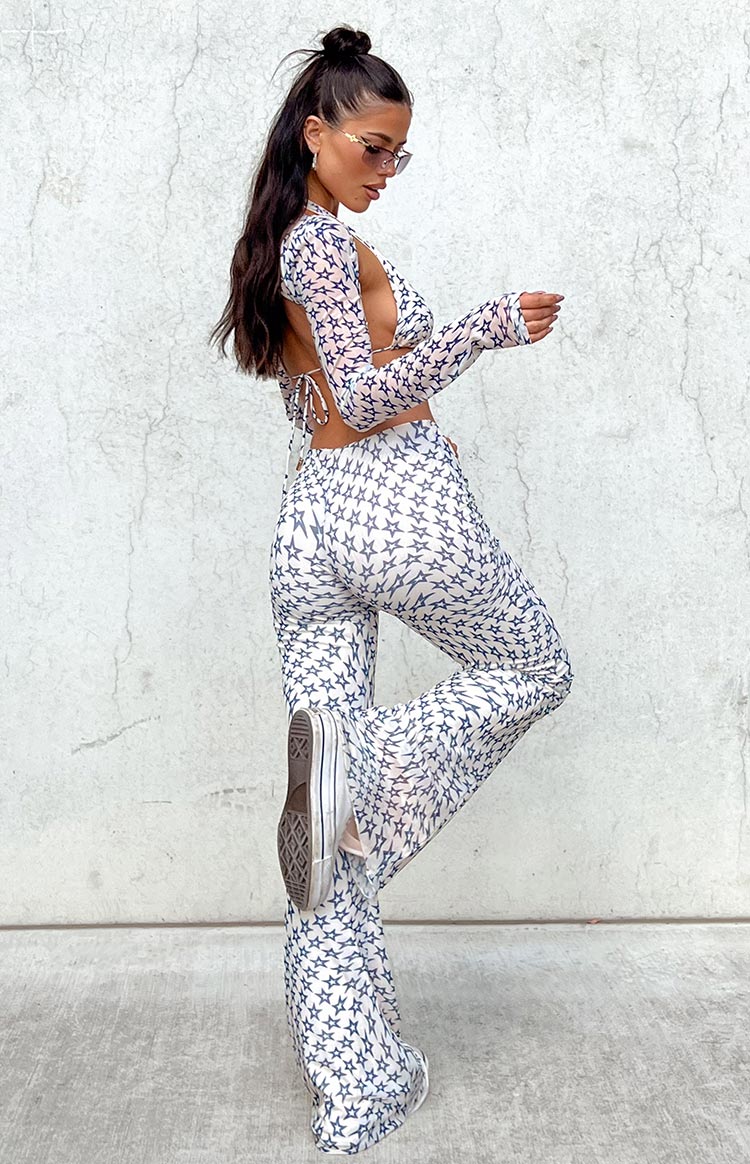 Side view of white mesh mid-rise pants with a black star print and flared sheer legs