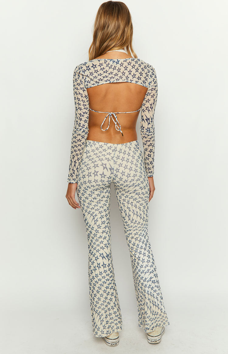 Rear view of cream mesh mid-rise pants with all-over blue star print, fitted through the thigh with flared legs