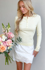 Scalloped hem of a white broderie mini skort with an all-over eyelet pattern