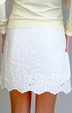 Rear view of a white broderie mini skort with intricate floral and eyelet patterns and a scalloped hem
