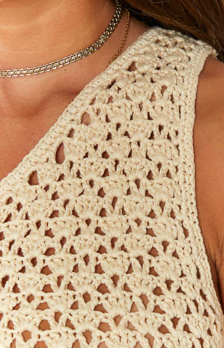 Close-up of the intricate open-knit crochet pattern on the beige mini dress