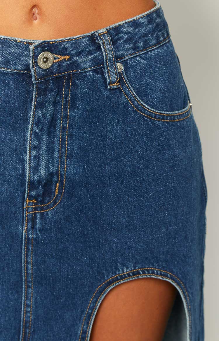 Close-up of the dark wash denim midi skirt showing the front button, pocket, and large side cutout