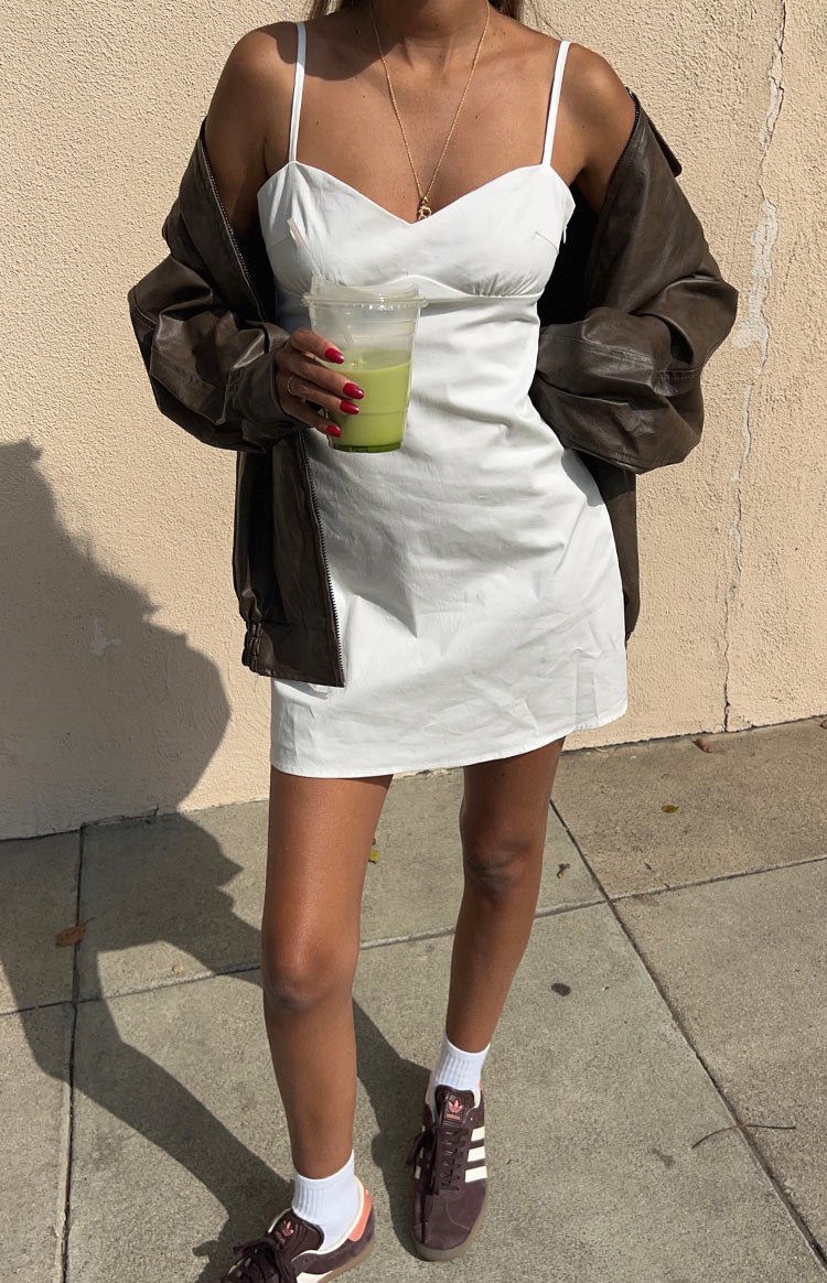 Full length view of a white mini dress with a sweetheart neckline, thin spaghetti straps, and a fitted A-line skirt