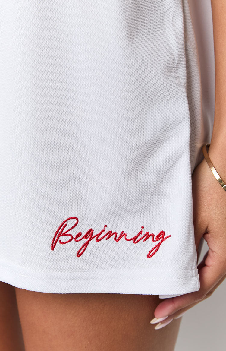 Close-up of the white jersey mini dress showing red embroidered 'Beginning' text near the hem