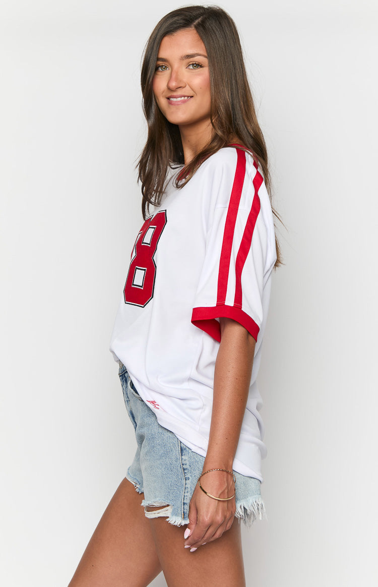 Side view of a white jersey mini dress with red stripes on the short sleeves and a red number 8