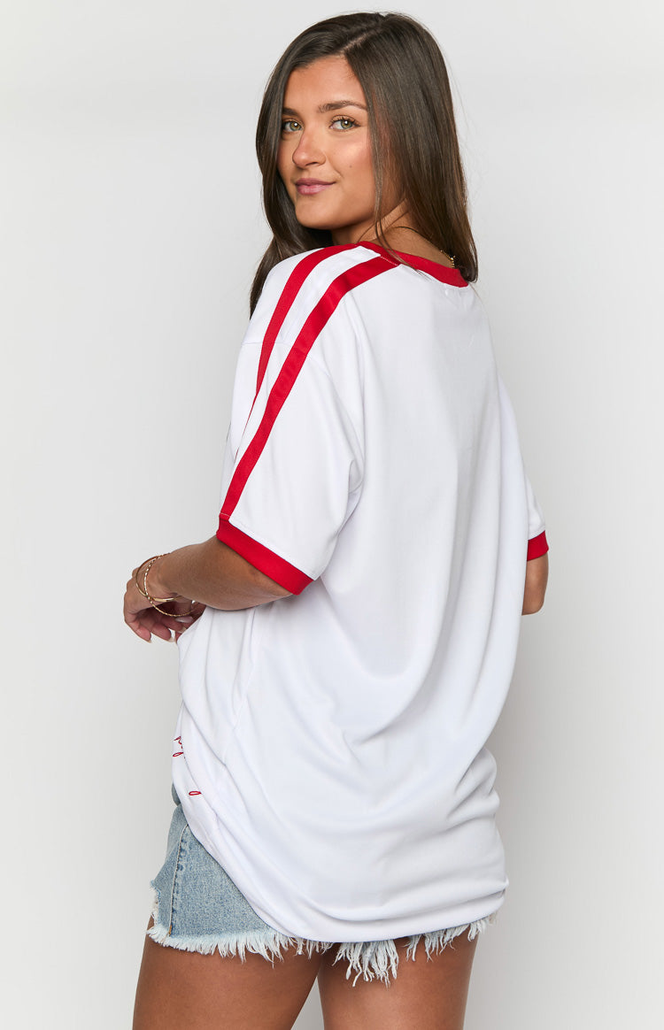 Side view of a white jersey mini dress with red trim on the crew neck and short sleeves, and red shoulder stripes