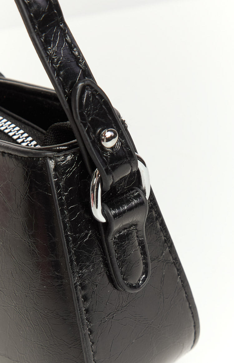 Close-up of the black textured PU material of the cross body bag, showing the silver hardware on the strap