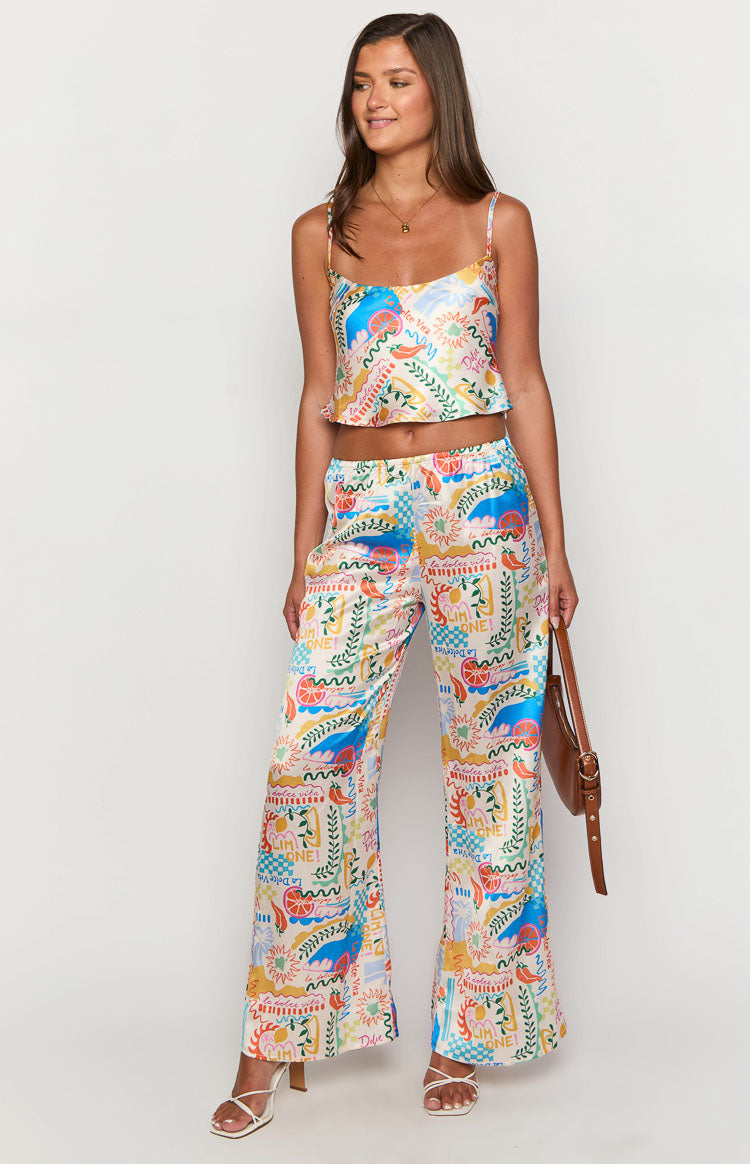 Front view of the flowing wide-leg pants in a vibrant multi-colour abstract print with citrus, chillies, and text