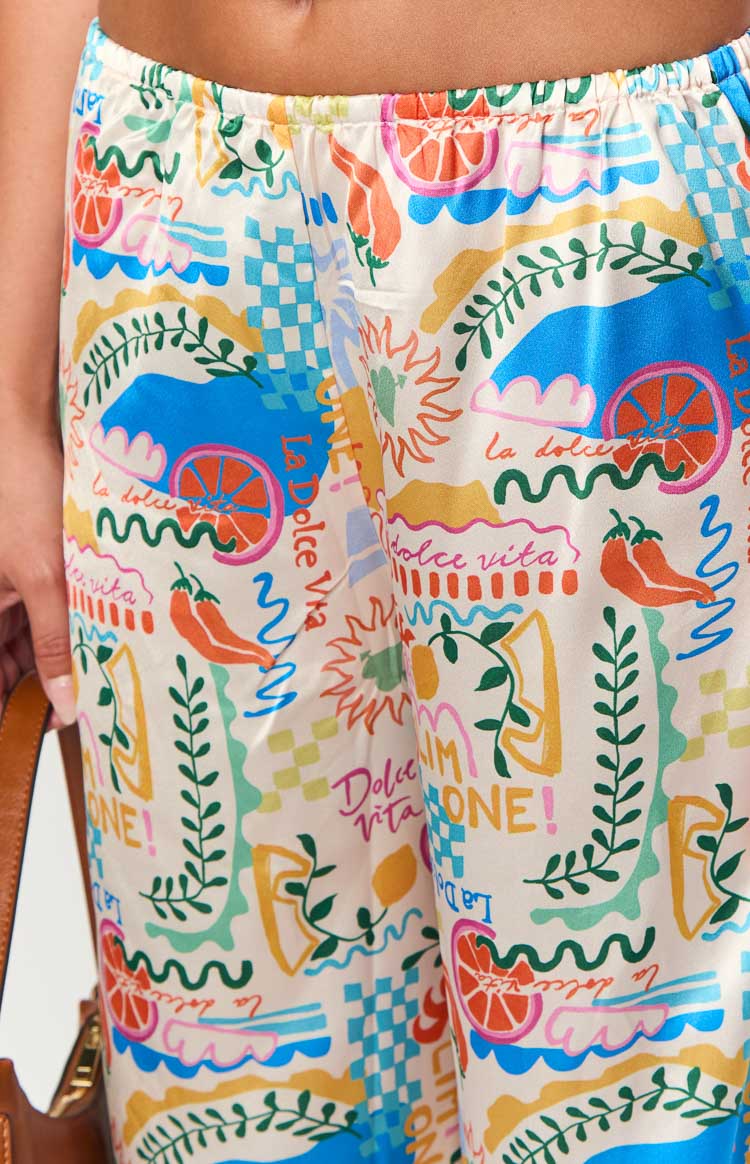 Close-up of the cream Dolce print pants showing elasticated waistband and colourful citrus, chili, and 'la dolce vita' motifs