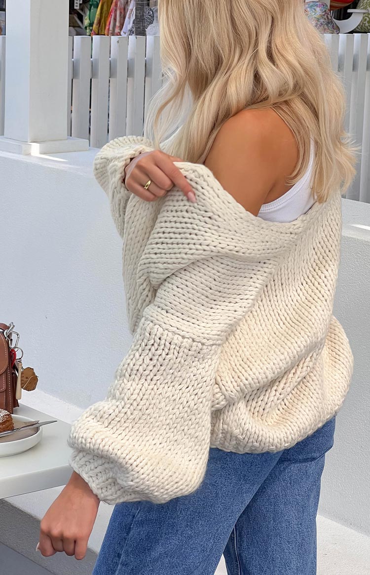 Side view of a cream chunky knit cardigan showing the thick ribbing and voluminous balloon sleeves