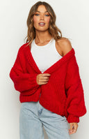 Close-up of the red chunky knit cardigan showing the oversized balloon sleeves and ribbed cuffs