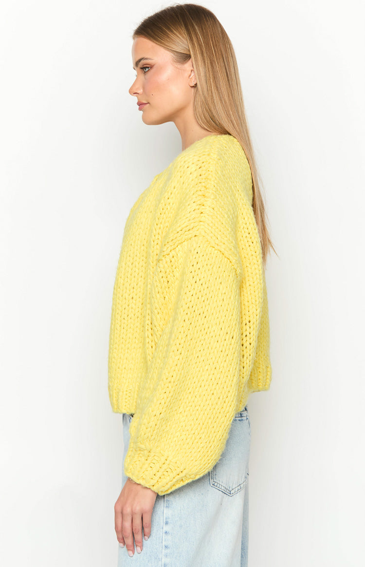 Side view of a yellow chunky knit cardigan with dropped shoulders and long voluminous sleeves with ribbed cuffs