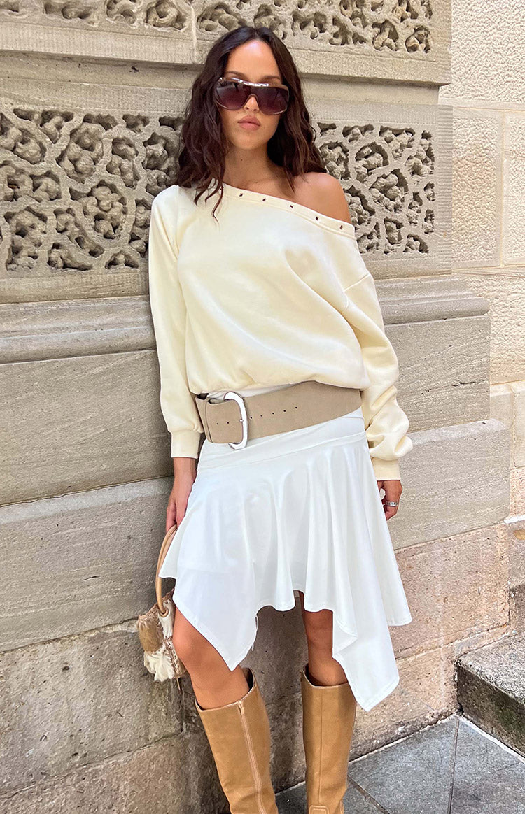 Cream long sleeve sweater with an asymmetric off-shoulder neckline and eyelet details along the collar