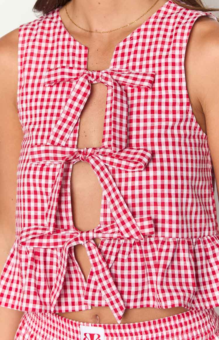 Close-up of the red gingham top showing multiple front cutouts with bow ties and a ruffled hem