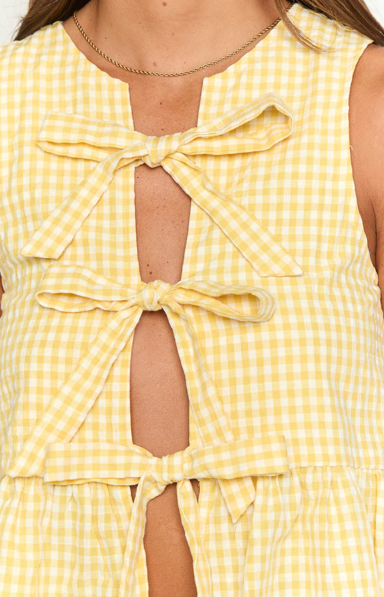 Front detail of a yellow gingham top with three tied bows creating a central opening