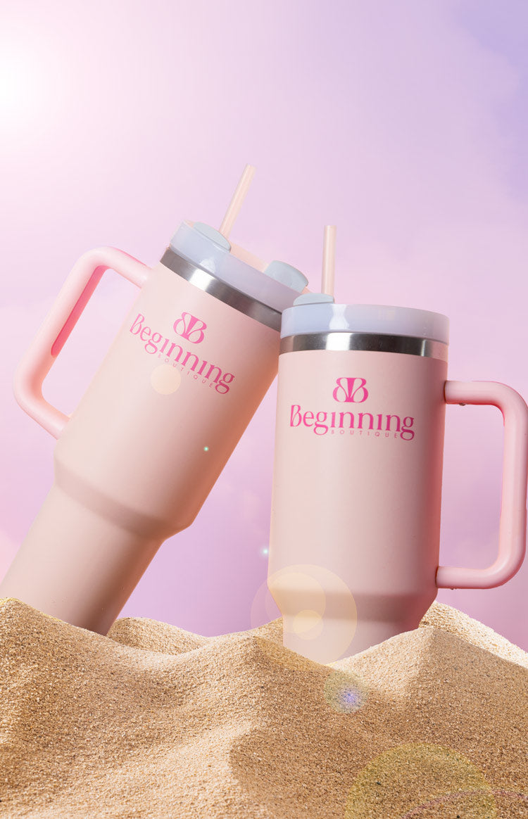 Angled view of two pink tumblers, one larger and one smaller, with handles, light blue lids, and straws