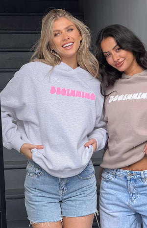 Grey marl oversized hoodie with bright pink bubble BEGINNING text, shown next to a beige hoodie