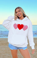Close-up of the white hoodie showing the three heart appliques and front kangaroo pocket