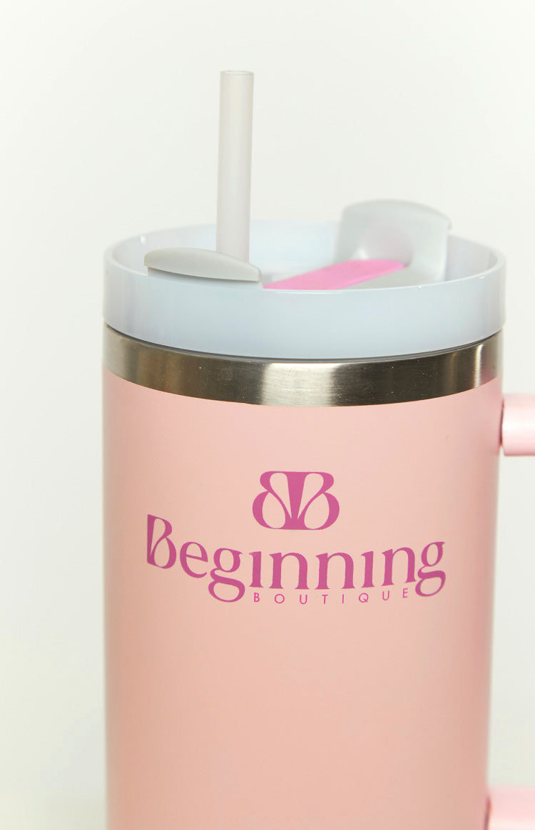 Close-up of the pink tumbler with a dark pink logo, white lid, clear straw, and silver rim detail