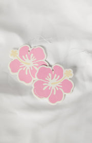 Two pink hibiscus-shaped air fresheners with light yellow centers and white strings, slightly overlapping