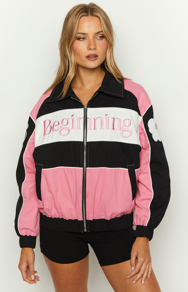 Front view of a black, white, and pink bomber jacket with pink 'Beginning' embroidery and a white flower patch