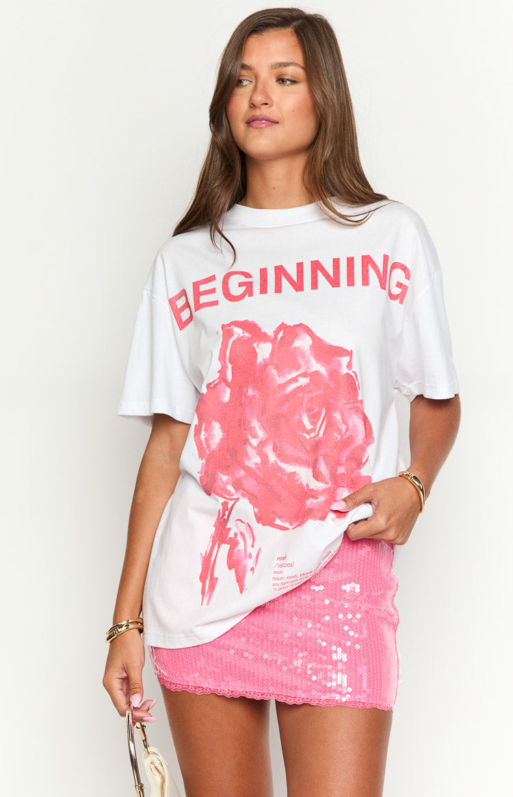Front view of an oversized white tee with a large pink rose graphic and 'BEGINNING' text