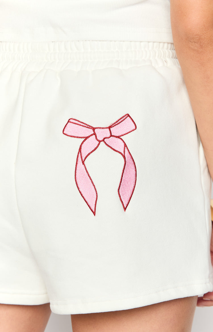 Close-up of the pink embroidered bow on the back of white shorts with an elasticated waistband