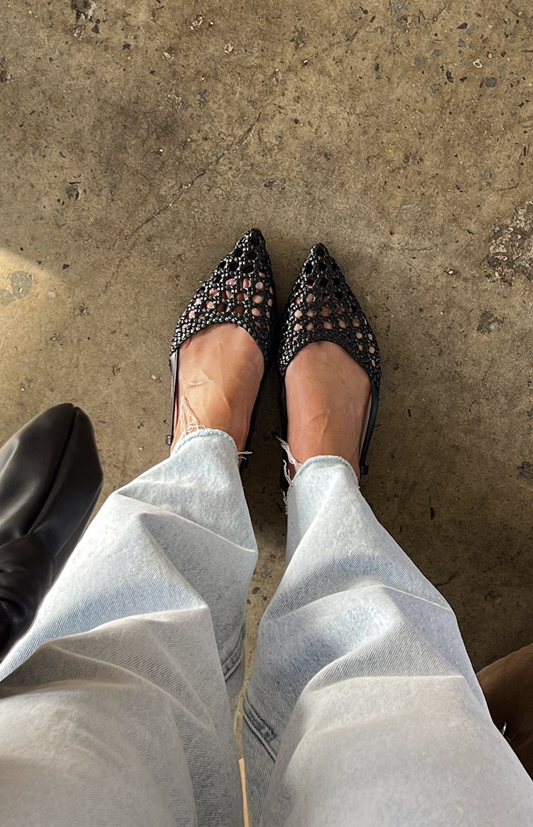 Overhead view of black woven mules showing the intricate mesh pattern and pointed toe design