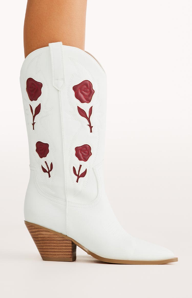 Side view of white cowboy boots with red rose embroidery and a stacked wooden heel