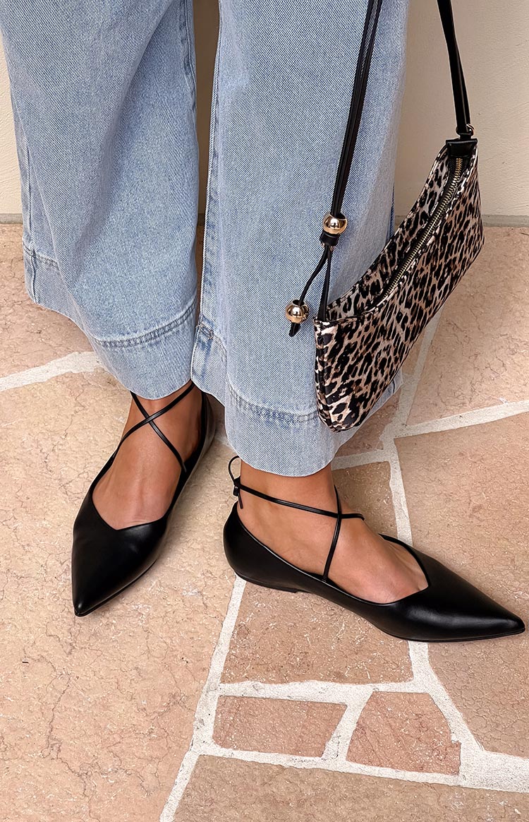 Black ballet flats with a pointed toe, V-cut vamp, and thin criss-cross ankle straps
