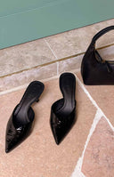 Close-up of black crocodile-embossed pointed-toe mule heels with a V-cut vamp and kitten heel