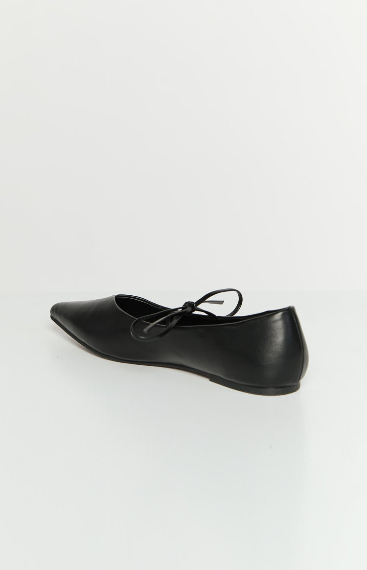 Side-rear view of a black ballet flat with a pointed toe and a tie detail on the vamp