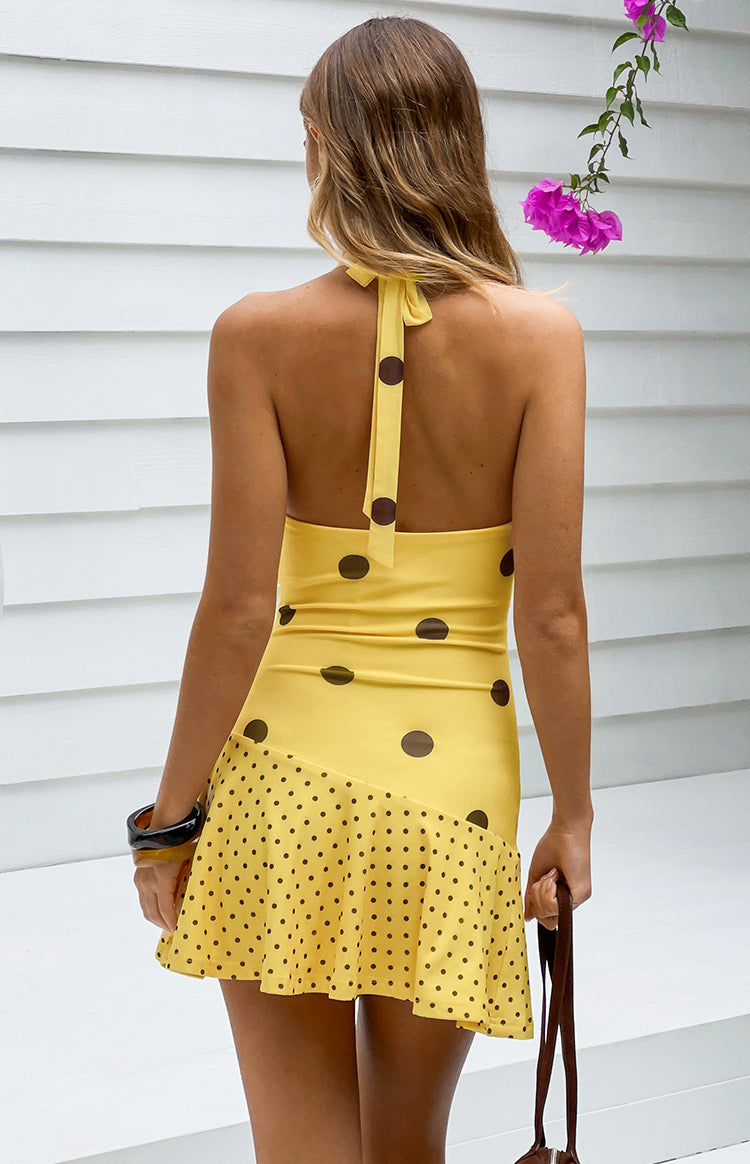 Rear view of a yellow polka dot mini dress with a halter neck tie and open back The bodice has large dots, the skirt has smal