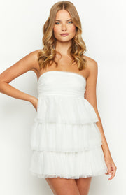 Front view of a white strapless mini dress with a ruched bandeau bodice and tiered tulle skirt