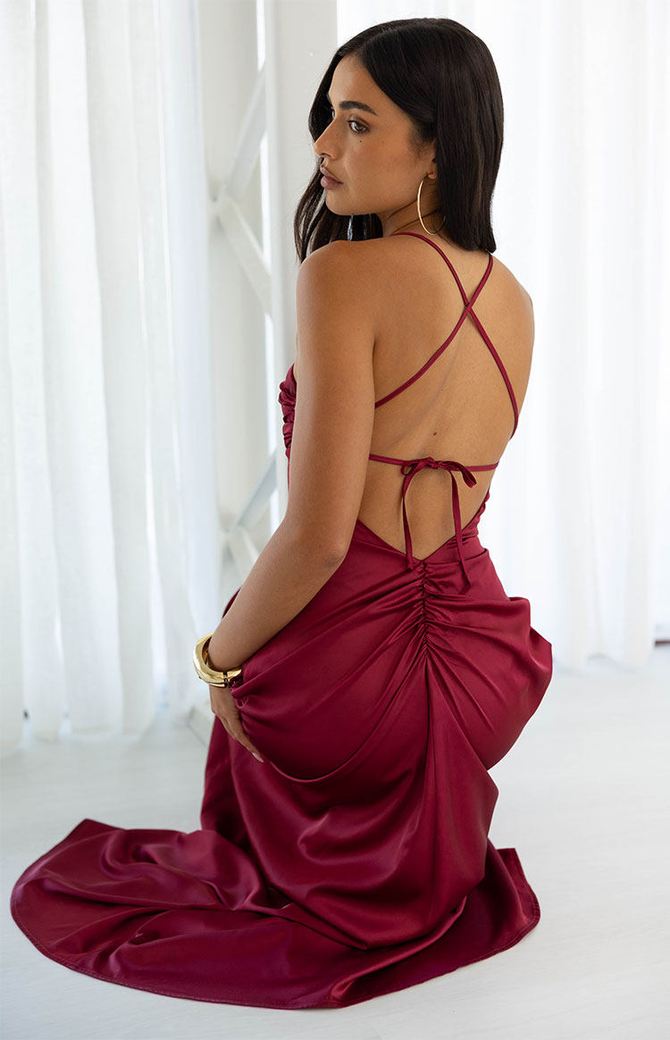 Rear view of a burgundy satin maxi dress showing criss-cross back straps, tie-back, and ruched skirt