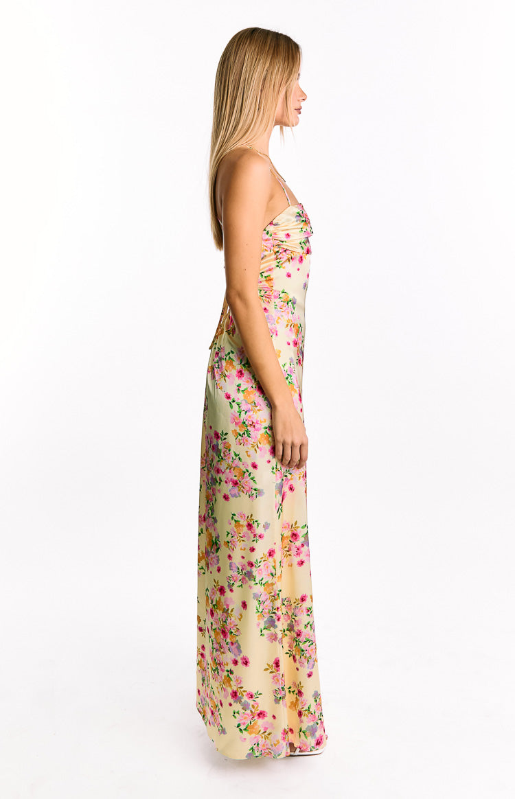 Side view of a yellow floral print satin maxi dress with ruched bust and spaghetti straps