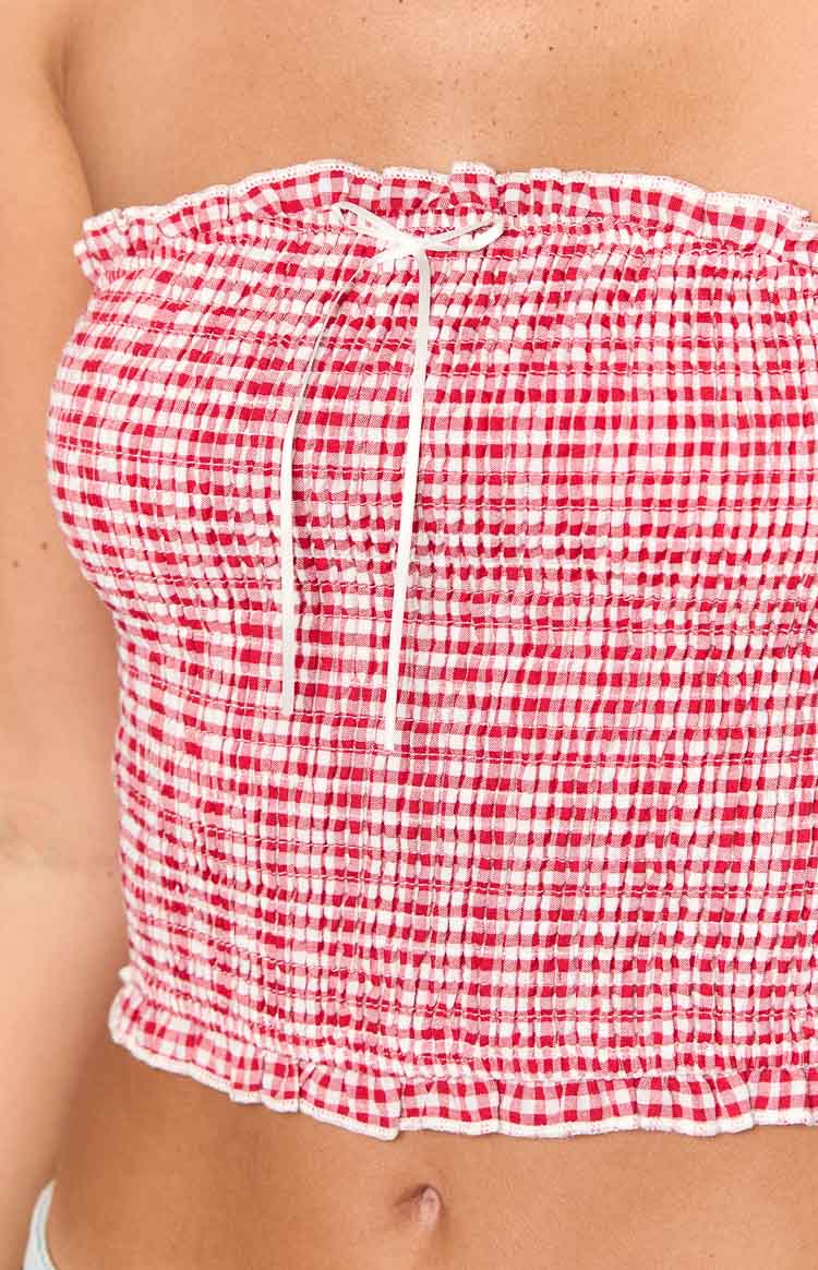 Close-up of the red gingham strapless top with smocked texture, ruffled edges, and white front tie