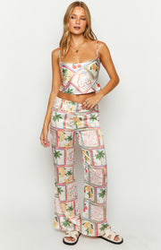 White satin wide-leg pants with a detailed patchwork print featuring lemons, cherries, and palm trees