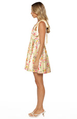 Side view of a yellow floral satin mini dress with tie shoulders and an A-line skirt