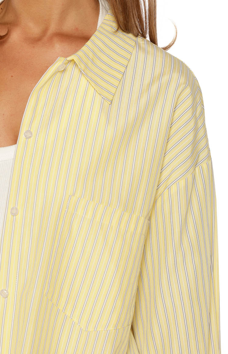 Close-up of the yellow striped shirt showing the collared neckline, dropped shoulder, and chest pocket