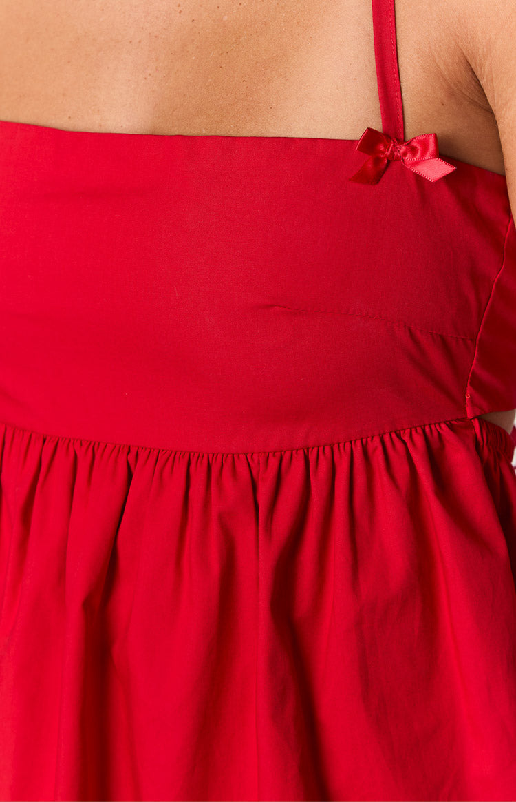 Close-up of the red mini dress showing the small red bow on the strap and the gathered waist seam