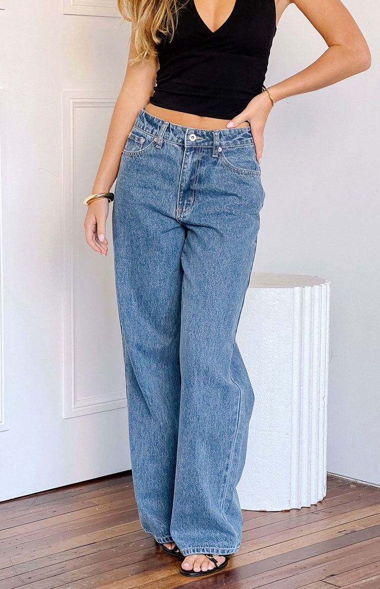 Mid wash blue slouchy jeans with a mid-rise waist, button closure, and wide leg