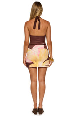 Rear view of the brown halter neck mini dress with a large yellow and pink floral print on the skirt and a thin brown belt