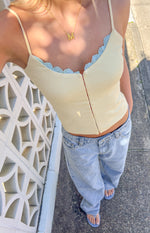 Top-down view of light wash low rise jeans with a relaxed fit and unique overlapping button closure