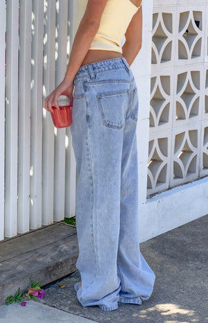 Rear side view of light wash low rise jeans with a baggy, wide-leg fit and visible back pockets, pooling at the ankles