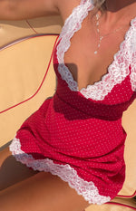 Close-up of the red polka dot mini dress with a deep V-neckline and hem trimmed with white lace